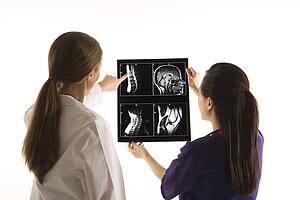Caucasian and Asian Chinese mid-adult female doctors analyzing x-ray. 