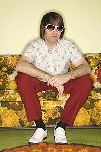Portrait of Caucasian mid-adult man wearing sunglasses sitting on colorful retro sofa.