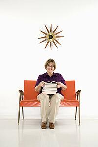 Woman sitting holding stack of books