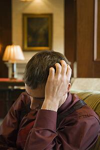 Businessman with hand to head and eyes closed looking depressed.