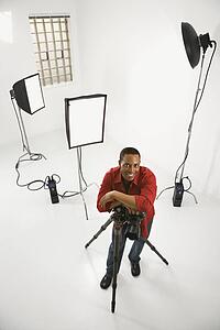 Young African American male adult photographer posing in studio.