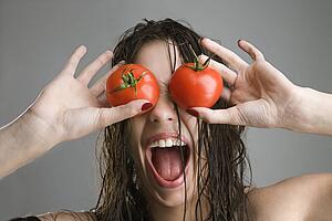 Woman with tomatoes covering her eyes
