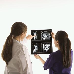 Caucasian and Asian Chinese mid-adult female doctors analyzing x-ray. 