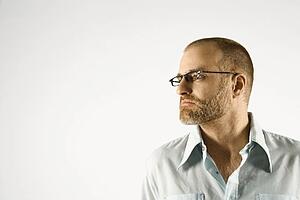 Head and shoulder portrait of man looking to side against white background.