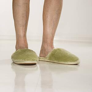 Senior woman's feet wearing green bedroom slippers.