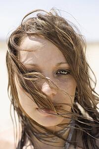 Portrait of Caucasian mid-adult woman with hair blowing across face looking at viewer.