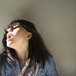Pretty young Asian woman with mouth open swinging head and hair around.