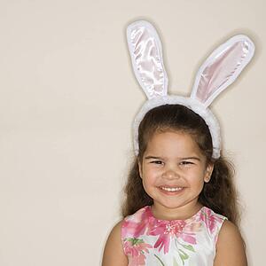 Young girl wearing bunny ears smiling and looking at viewer.