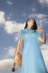 Caucasian young adult woman in retro clothing looking up at sky.