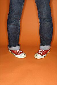 Person in jeans and sneakers with feet turned inward