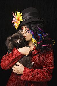 Woman kissing black Pomeranian dog 