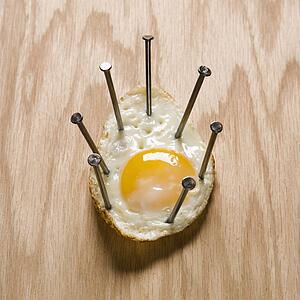 Fried egg nailed to wood