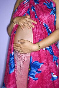 Close up portrait of expecting female with hands on stomach