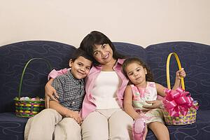 Family sitting on couch with Easter baskets smiling and looking at viewer.