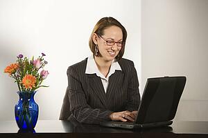 Businesswoman sitting at desk smiling with laptop computer