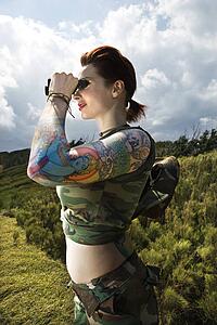 Attractive tattooed Caucasian woman standing looking through binoculars 