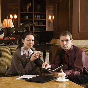 Caucasian mid adult businessman and woman drinking coffee and looking at viewer.