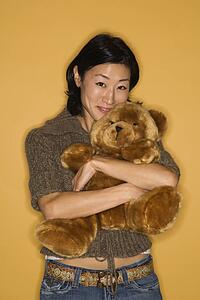 Pretty mid adult woman hugging brown teddy bear