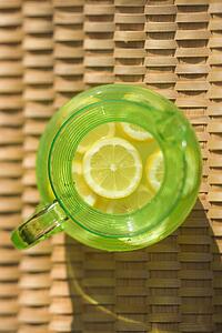Overview of green plastic pitcher of lemonade with sliced lemons.