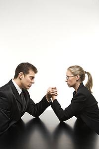 Businessman and businesswoman arm wrestling on table