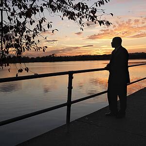 African-American man standing by water at sunset in Washington, D. C., USA.
