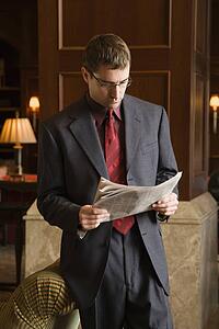 Caucasian mid adult buisinessman reading newspaper.