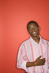 Man smiling with hand on abdomen standing against red background.