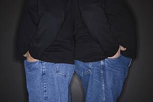Bodies of mid adult identical twin men standing back to back.