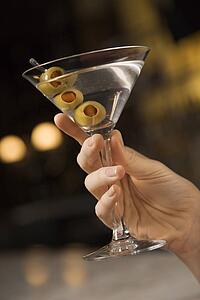 Mid adult female hand holding a martini with three olives