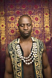Man wearing embroidered African vest and beads.