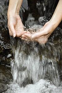 Female hands in a running stream