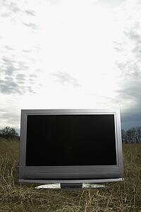 Flat panel television set in grassy field