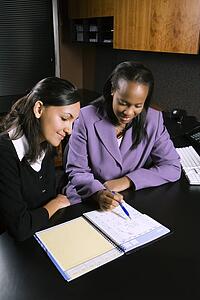 African-American and Indian young adult business women working together in office.
