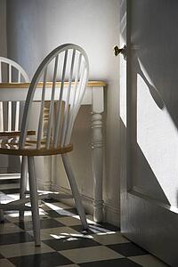 Sunlight lit kitchen with dinette and black and white checkerboard tiled floor.