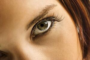 Close up of young woman's green eye with makeup.