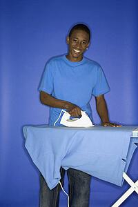 Boy smiling and ironing shirt 