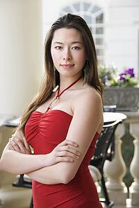 Woman in red dress with arms crossed looking