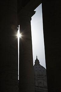 Sun peeking through doric columns in Saint Peter's Square in Vatican City, Italy.
