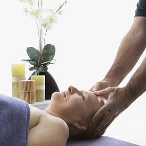 Massage therapist massaging temples of woman lying on massage table