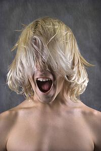 Male Caucasian teen with hair over face screaming.