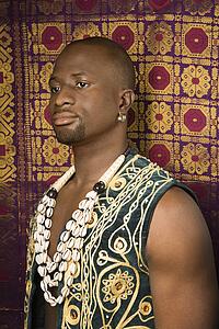Man wearing embroidered African vest and beads