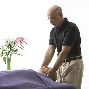 Massage therapist massaging face of a woman lying on massage table