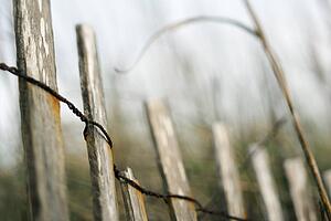 Wooden fence with rusted wiring