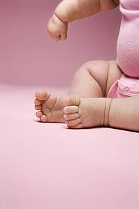 Close up of Asian babys legs and feet and arm.