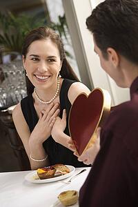 Man giving a heart shaped box of chocolates to woman 