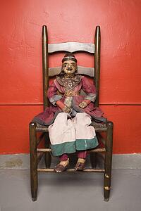 Wooden puppet sitting on chair