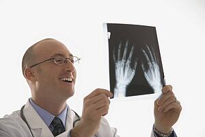 Caucasian mid adult male physician holding up hand xrays.