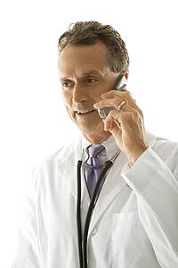 Portrait of a mid-adult Caucasian male doctor with stethoscope around his neck talking on cell phone.