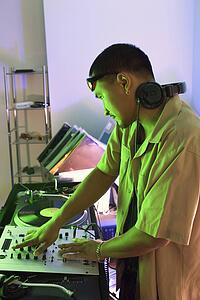 Profile of young DJ with mixing equipment, turntables and headphones.