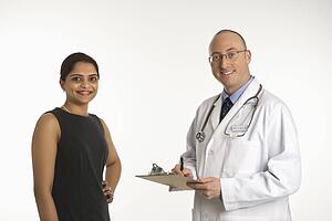 Caucasian mid adult male physician talking with Indian woman patient.